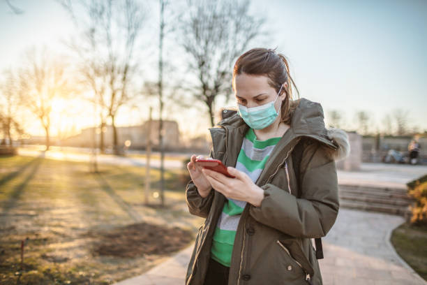 istock Woman With Mask Using Phone in the city Park 1212893201