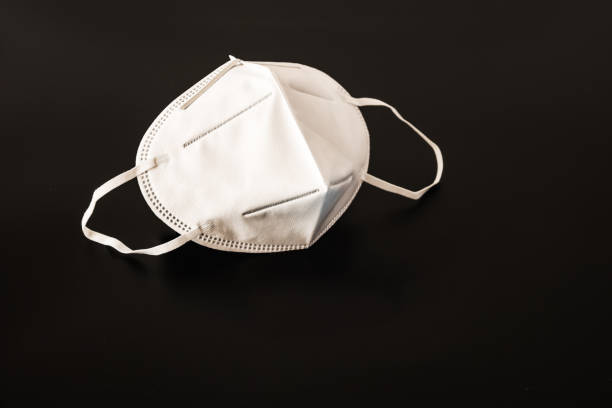 istock Disposable medical mask in black background 1212893388