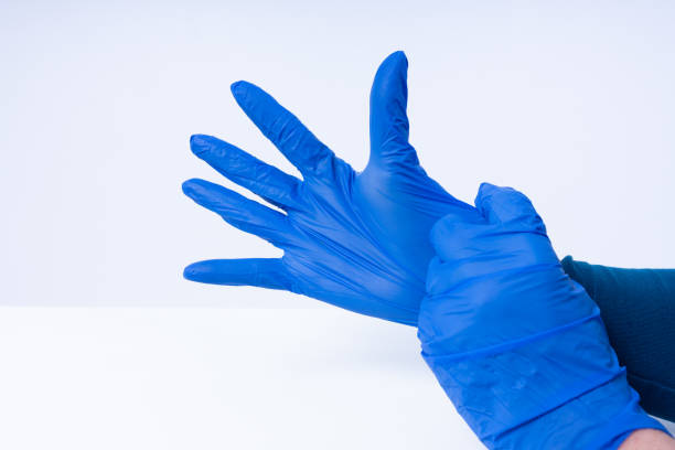 hands putting on blue nitril gloves - nitril imagens e fotografias de stock