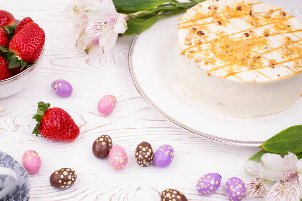 istock Cake covered with white cream and nuts, strawberries and chocolate eggs in a multi-colored falge. 1212895244