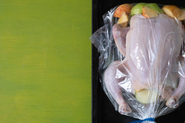 istock Raw chicken with apples in the plastic oven bag on the black baking tray 1212895825