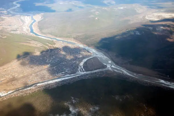 Siberian city at the confluence of the Kuta river with the Lena river from an airplane. The city of Ust-Kut in the taiga between the hills in the Irkutsk region in April.