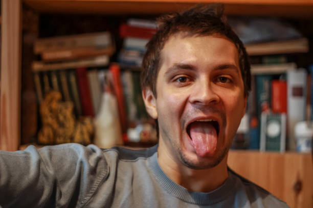 istock young attractive man looking at the camera and showing tongue. 1212906668