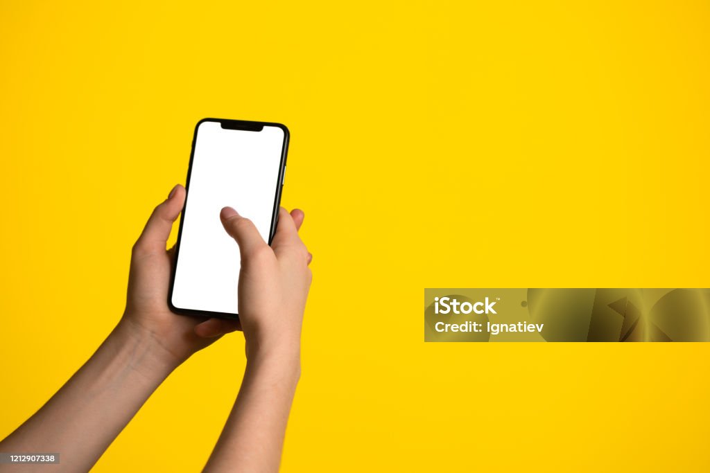 Close-up of a hand holding bezel-less smartphone on a yellow background Hand Stock Photo