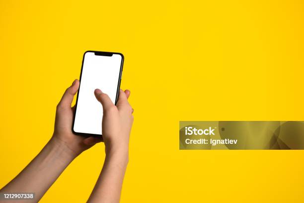 Closeup Of A Hand Holding Bezelless Smartphone On A Yellow Background Stock Photo - Download Image Now