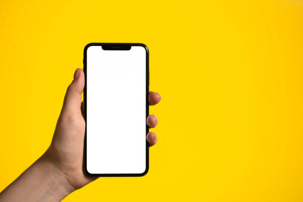 Hand holding mobile phone with blank white full screen Hand holding mobile phone with blank white full screen on a yellow background hand holding phone stock pictures, royalty-free photos & images