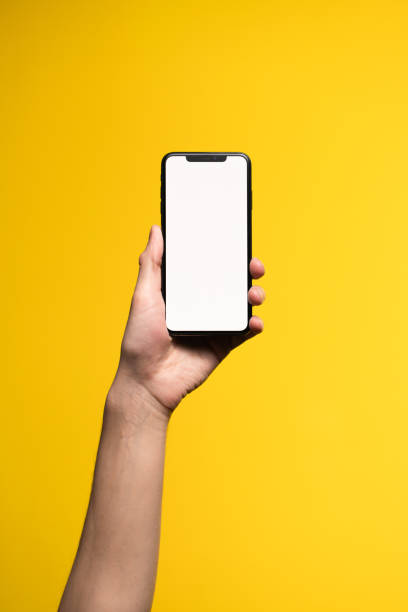 istock A man typing with one hand on a white screen phoneon a yellow background. 1212907435