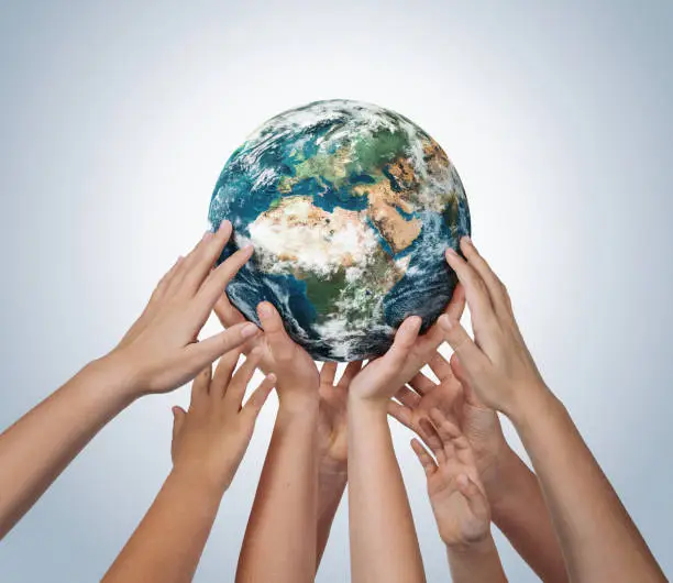 Many children hands holding planet earth isolated on blue background with copy space. Element of this image furnished by NASA ( https://earthobservatory.nasa.gov/blogs/elegantfigures/2011/10/06/crafting-the-blue-marble/ )