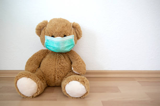 istock Teddy bear with face mask in front of white wall 1212910280