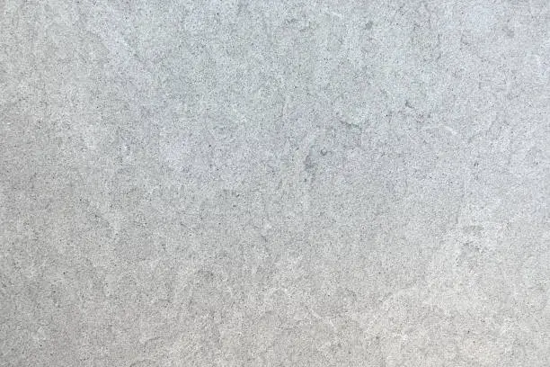 Marbled pattern of a smooth light gray stone slab in closeup