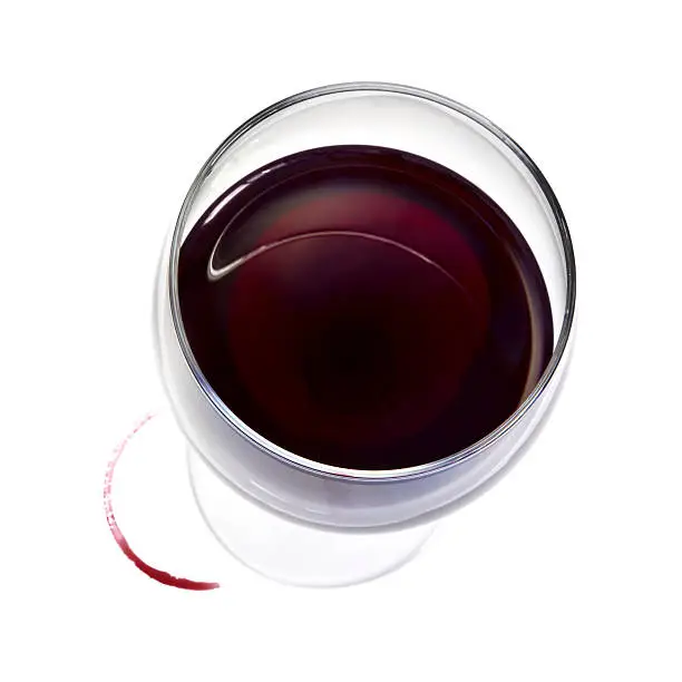 Photo of Top down view of glass of red wine with spill ring on white