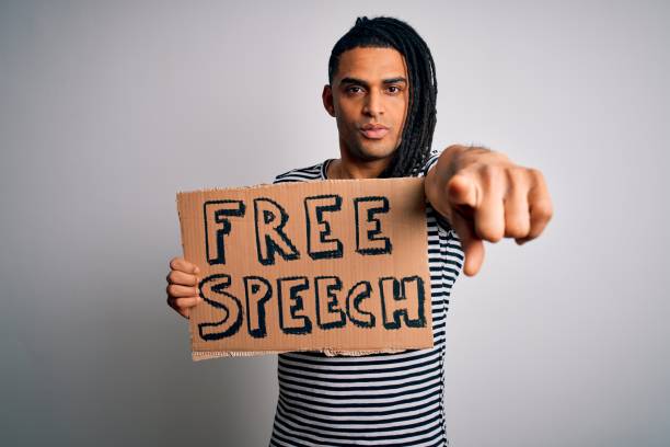 istock Young african american man with dreadlocks holding banner with free speech message protest pointing with finger to the camera and to you, hand sign, positive and confident gesture from the front 1212915669
