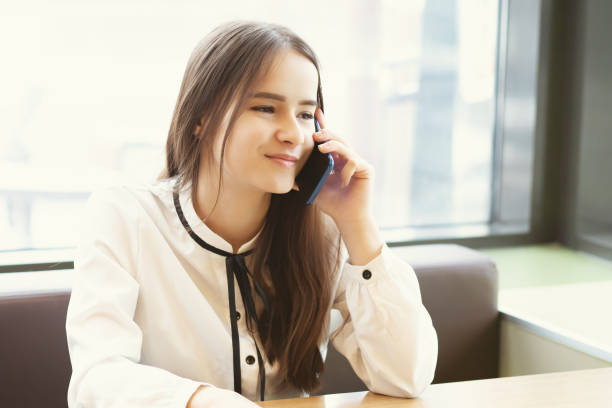istock Young woman office worker in a cafe with a smartphone, talking, smiling 1212919737