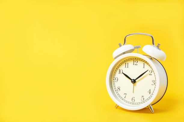 istock White alarm clock on a yellow background. Place for text 1212920771