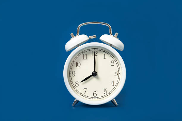 istock White alarm clock on a blue background. Place for text 1212920807