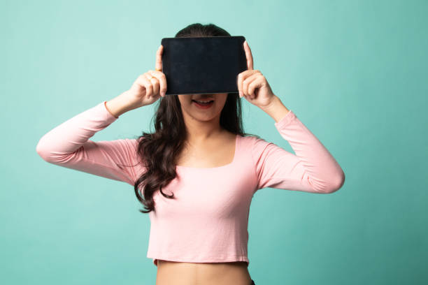 istock Young Asian woman with a computer tablet over her face. 1212928406
