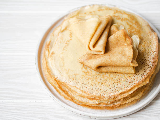 istock Stack Russian homemade thin pancakes on white plate on wood background. Traditional wheat pancakes for Shrovetide. 1212928506