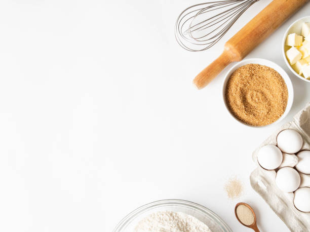 istock Frame of various baking ingredients - flour, eggs, sugar, butter, dry yeast, and kitchen utensils on white background. Top view. Copy space 1212928599