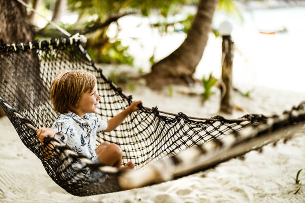 istock Cute boy having fun while relaxing in hammock on the beach. 1212928612