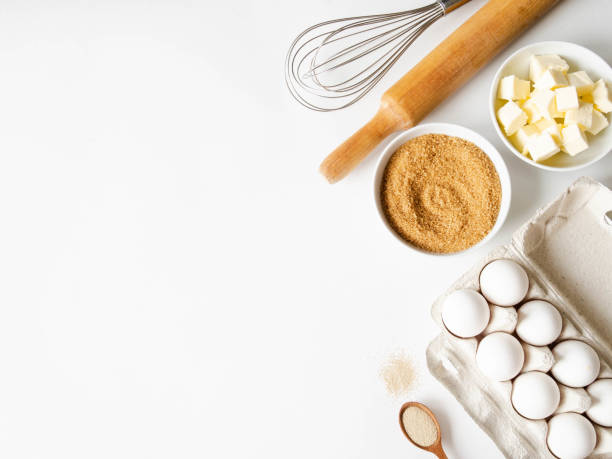istock Various baking ingredients - eggs, sugar, butter, dry yeast and kitchen utensils on white background. Top view. 1212928621