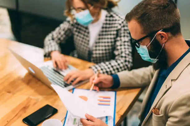Businesspeople wearing masks in the office for safety during COVID-19 pandemic