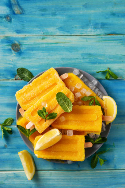 istock Vertical shot of yellow refreshing ice sorbet on blue rustic background 1212934134