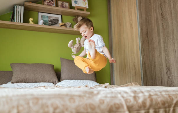 istock Little boy jumping on the bed 1212937393