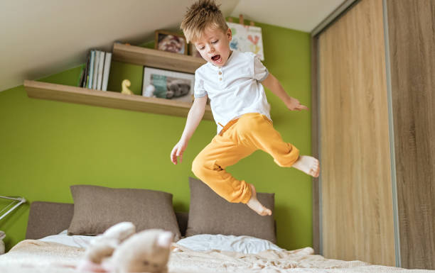 istock Little boy jumping on the bed 1212937439