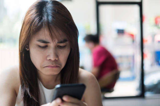 istock young asian Businesswoman feeling bored during using smartphone at office. Emotion, Technology and lifestyle concept 1212940617