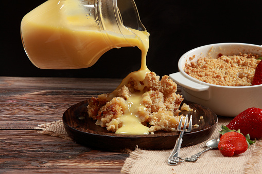 Traditional delicious British Apple Crumble with Custard Topping and side-fruits