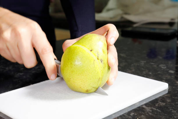 istock Slicing a pear with a knife on a cutting board 1212947661