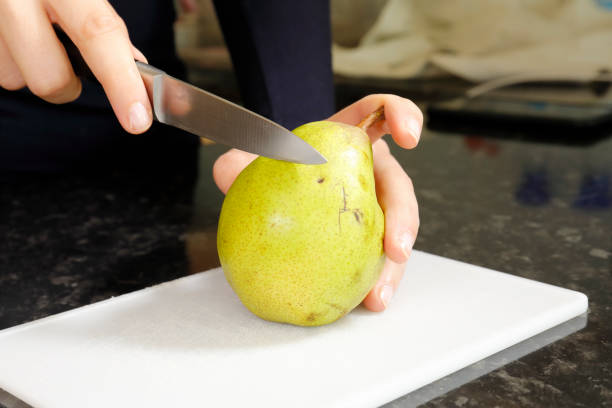 istock Slicing a pear with a knife on a cutting board 1212948660