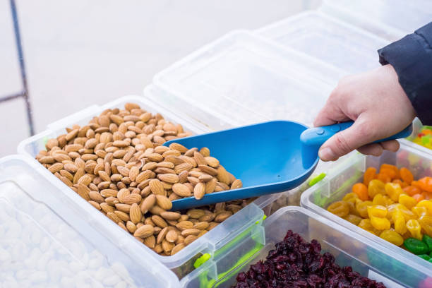 istock Close-up of a seller using a spatula, picking almonds from a dried-fruit store counter. 1212950362