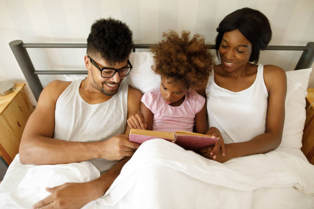 istock Happy family reading an interesting book in bed 1212952160