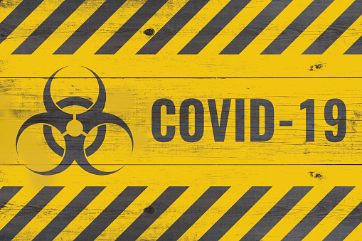 bio hazard sign and covid-19 message on aged gray wooden wall