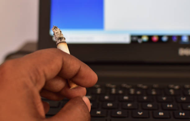 istock Smoking cigarette on the desk with laptop computer. Smoking to relieve stress at work but unhealthy 1212962838