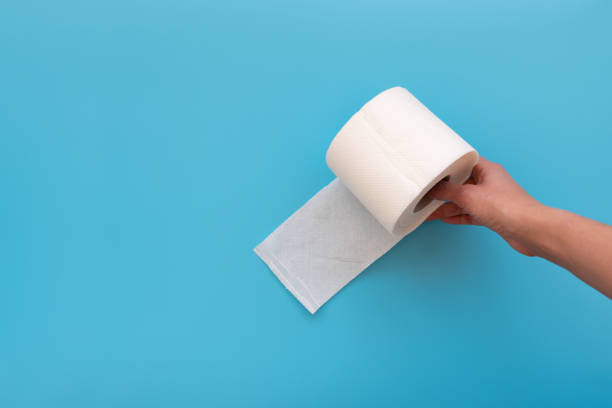 istock Hand holding toilet paper rolls on blue background. Copy space 1212969242