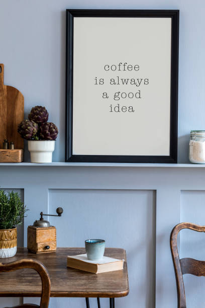 istock Interior design of kitchen space with black mock up photo frame, wooden table, chairs, herbs, cutting board, food and kitchen accessories in modern home decor. 1212977272