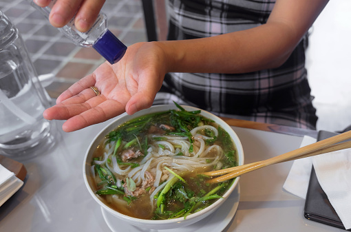 Close up shot of Indonesian female hands applying hand sanitizer gel before eating food