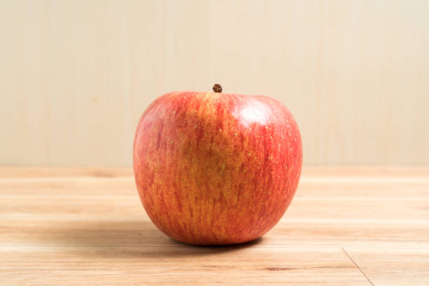 sosteniendo una manzana en la mano desde abajo aislada sobre fondo blanco - single hit fotografías e imágenes de stock