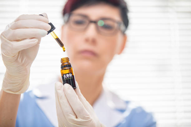 Portrait of Female Doctor Holding CBD Oil Drops - Stock Photo Portrait of Female Doctor Holding CBD Oil Drops. medical cannabis stock pictures, royalty-free photos & images