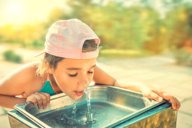 istock Cute thirsty girl drinks water from drinking sink 1212980557