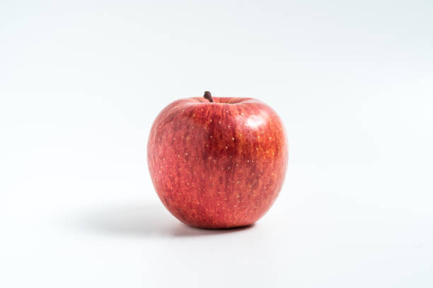 sosteniendo una manzana en la mano desde abajo aislada sobre fondo blanco - single hit fotografías e imágenes de stock