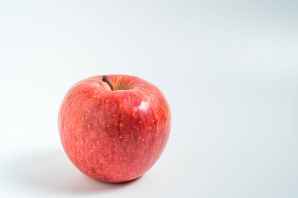 sosteniendo una manzana en la mano desde abajo aislada sobre fondo blanco - single hit fotografías e imágenes de stock