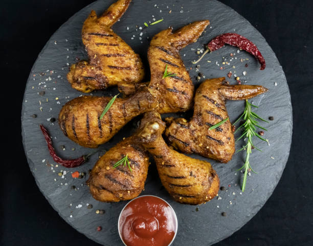 istock grilled chicken legs and wings with red sauce on a black stone surface 1212982372