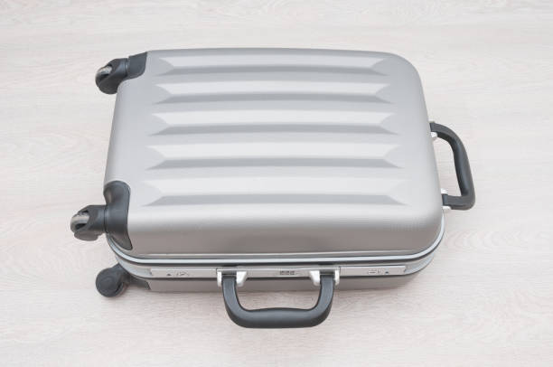 istock Gray  suitcase close up on wooden background 1212982395