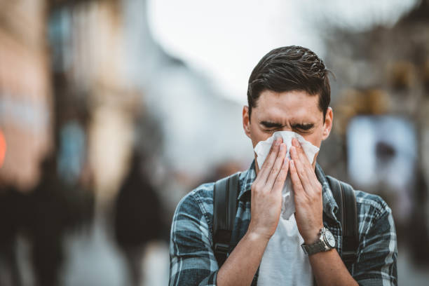 istock Cold and flu. Man blowing his nose with a tissue 1212983215