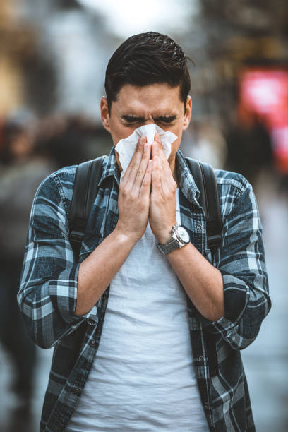 istock Cold and flu. Man blowing his nose with a tissue 1212983262