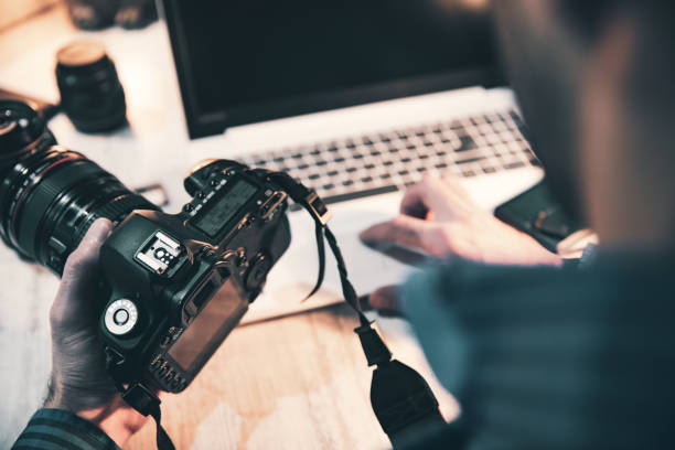 istock photographer hand camera and computer on desk 1212983422