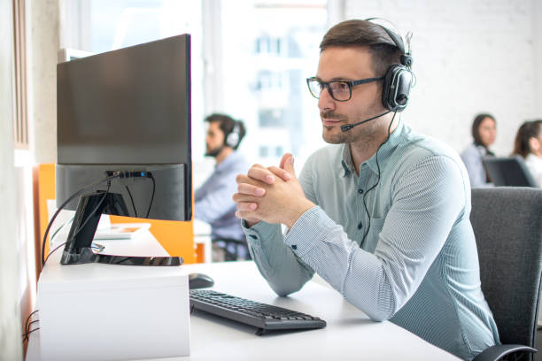 istock Customer service support operator man with headphones and microphone listening to his client in call center 1212984210
